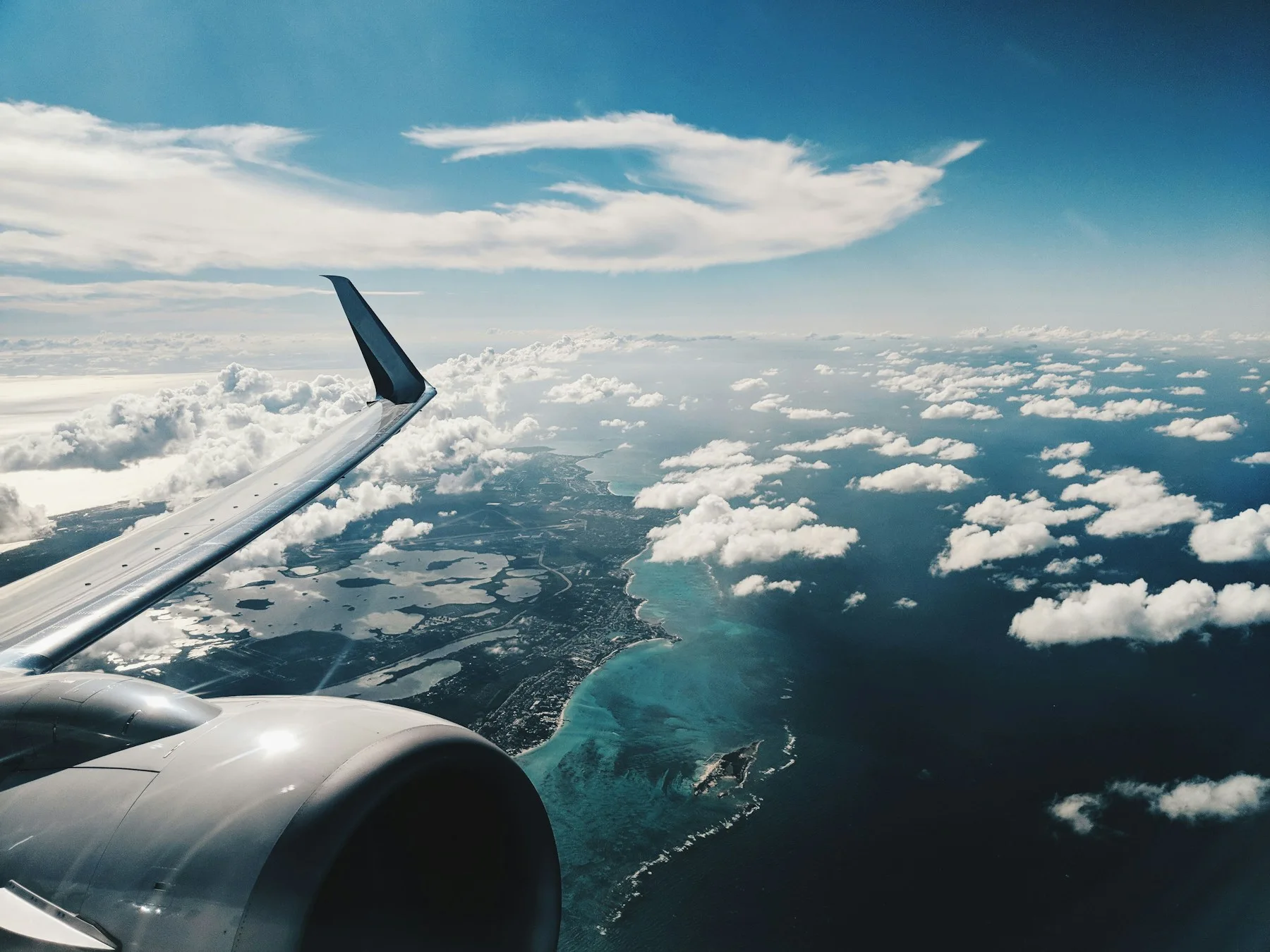 雲の上へと広がる空と、海を渡る飛行機の翼